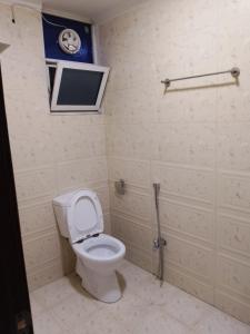 a bathroom with a toilet and a tv on the wall at Shah Gee Guest House in Islamabad