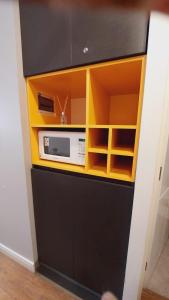 a black and yellow cabinet with a microwave in it at Hermoso y elegante monoambiente in Cochabamba