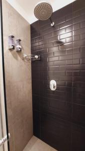 y baño con ducha y pared de azulejos negros. en Hermoso y elegante monoambiente, en Cochabamba