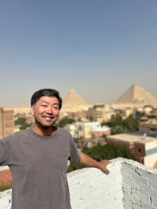 a man standing on a wall with pyramids in the background at LOAY PYRAMIDS VIEW in Cairo