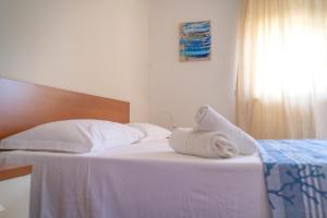a white bed with a towel on top of it at Agua Residence in Noto
