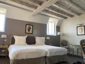 een slaapkamer met een groot bed met witte lakens en kussens bij Château Sainte Sabine in Sainte-Sabine