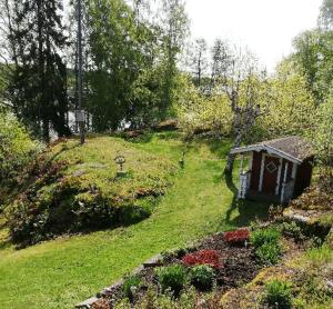 a garden with a small house on a hill at House with lake plot and own jetty on Skansholmen outside Nykoping in Nyköping