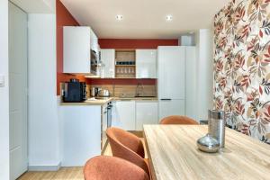 une cuisine avec des placards blancs et une table en bois avec des chaises dans l'établissement Yann : Détente et Confort près de Rouen, à Sotteville-lès-Rouen