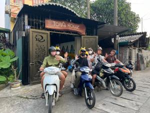 un groupe de personnes transportant des motocyclettes devant une maison dans l'établissement Tom's house motorbikes tour and homestay, à Làng Me