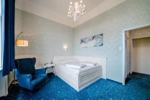 ウィーンにあるホテル ゴールデン スピンのベッドルーム1室(ベッド1台、椅子、シャンデリア付)