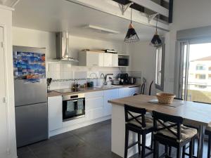 una cocina con armarios blancos y una mesa con sillas. en Appartement 40m2 - Bord de mer en Frontignan