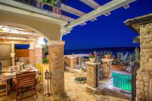 an outdoor dining room with a view of the ocean at night at Two houses Villa Diana Jesenice with pool, sauna, playground in Jesenice