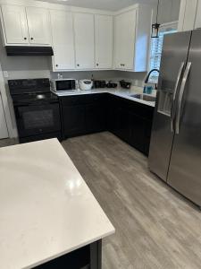 a kitchen with white cabinets and a stainless steel refrigerator at Amys Place Remolded 4 Bedroom near Arkansas Tech in Russellville