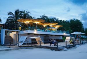 a building on the beach with people sitting under umbrellas at Hotel Tropical Inn in Tierra Bomba