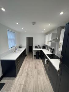 a large kitchen with white counter tops and wooden floors at Beautiful Anfield Family Home in Liverpool