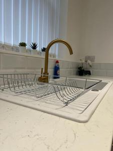 a kitchen sink with a metal drying rack on it at Beautiful Anfield Family Home in Liverpool