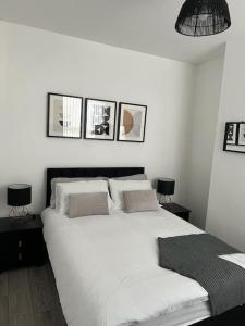 a bedroom with a white bed with three pictures on the wall at Beautiful Anfield Family Home in Liverpool