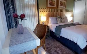 a bedroom with a bed and a table with a vase of flowers at Bhotani Lodge in Port Elizabeth