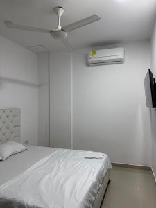 1 dormitorio blanco con 1 cama y ventilador de techo en Espectacular apartamento central, en Montería