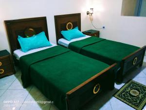 2 camas en una habitación con sábanas verdes en hotel khaouni bourdj bou arraredj, en Bordj Bou Arreridj