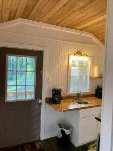 eine Küche mit einer Theke, einem Waschbecken und einem Fenster in der Unterkunft Valley View Cabin - Buffalo Point in Maumee