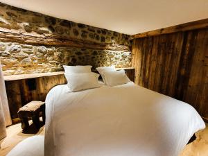 a bedroom with a white bed and a stone wall at Les Fermes de Cal Panche : La Ferme in Les Angles