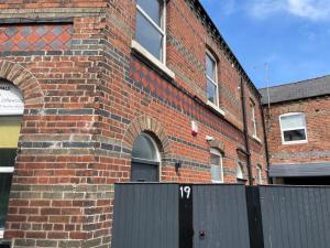 ein Backsteingebäude mit einem schwarzen Tor davor in der Unterkunft The Old Dance School - 1 and 2 Bedroom Apartments in the Heart of Chesterfield in Chesterfield