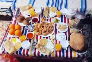 Casa Plasa Grande chefchaouen في شفشاون: طاولة مع طعام الإفطار على بطانية مخططة
