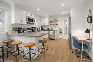 a kitchen with white cabinets and bar stools at Brand New Designer's Modern 1BR Home 1min to I-5 in Lynnwood +19 photos