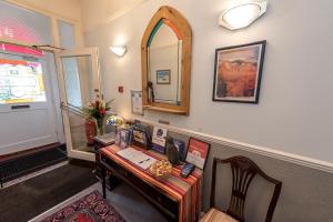 Habitación con escritorio y espejo en la pared. en The Strand Hotel, en Bournemouth