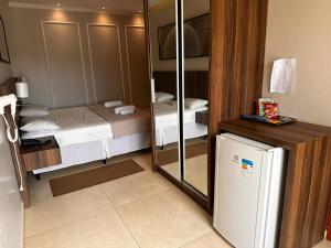 a small room with two beds and a refrigerator at Hotel Eden in Eugênio Penzo