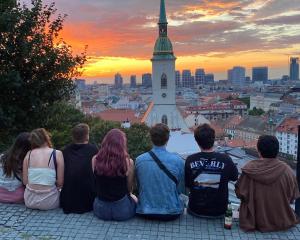 Eine Gruppe von Menschen, die auf einem Felsvorsprung sitzen und die Stadt ansehen in der Unterkunft Urban Elephants Hostel in Bratislava