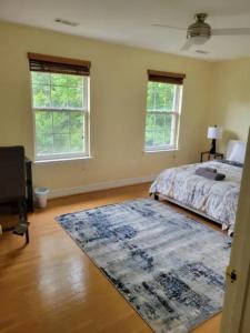 een slaapkamer met een bed, een tapijt en 2 ramen bij 1 bedroom in a cheerful home with indoor fire place in Fort Washington