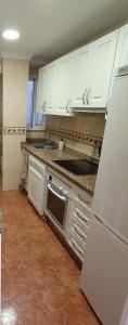 a kitchen with white cabinets and a sink and a refrigerator at Apartamento Fuengirola Centro in Fuengirola