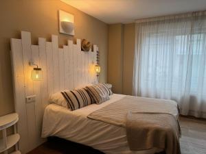 a bedroom with a bed with a white headboard and a window at Acadie Saint Victor - Hôtel restaurant - Face mer - Chatelaillon plage in Châtelaillon-Plage