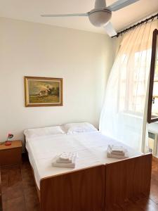a bedroom with a bed with white sheets and a window at Residence La Scogliera in Alassio