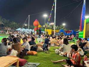 uma multidão de pessoas sentadas na relva à noite em Homestay Ocean Park 2 em Hanói