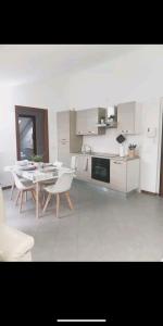 - une cuisine avec des appareils électroménagers blancs, des tables et des chaises dans l'établissement Suite Room Malpensa apartment, à Cardano al Campo