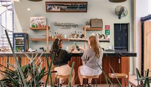 zwei Frauen sitzen an einem Tresen in einem Friseursalon in der Unterkunft Hostik Hostal in Mérida