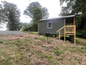 a small gray house with a porch on a field at Camping Cabin with private Bathroom in Maumee