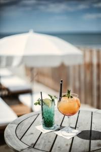 dos cócteles sentados sobre una mesa de madera en Hôtel La Plage 5 étoiles La Grande Motte en La Grande-Motte