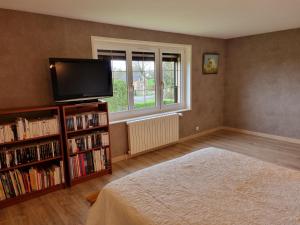 een slaapkamer met een bed en een televisie en een boekenplank bij Vaucelles city in Vaucelles