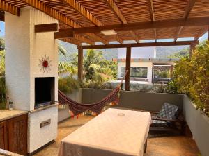 an outdoor patio with a table and a fireplace at Casa aconchegante in Maresias