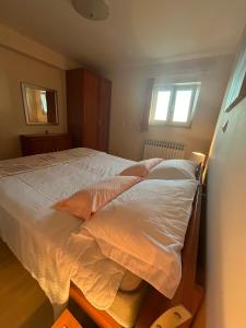una camera da letto con un letto con lenzuola bianche e due finestre di Apartman ŠTRK a Sukošan (San Cassiano)