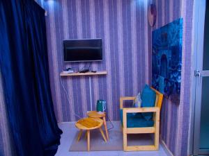 Habitación con pared morada, TV y silla. en Dakar International House en Dakar