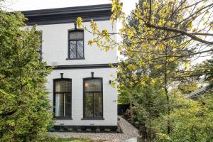 Casa blanca con ventanas y árboles negros en Cosy Dutch Delight Apartment, en Santpoort-Zuid