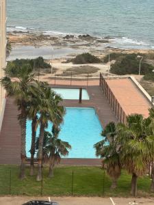a swimming pool next to a beach with palm trees at Apartment Sea Breeze I La Manga in La Manga del Mar Menor