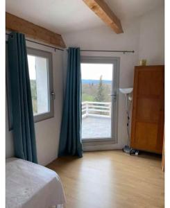 una camera da letto con una grande finestra con tende verdi di L’escapade, coeur de la nature a Saint-Hippolyte-du-Fort