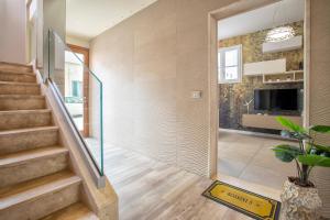 un pasillo de una casa con escaleras y TV en Luxury Sofia Home Alghero, en Alghero