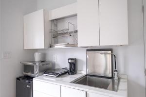 kuchnia z białymi szafkami, zlewem i kuchenką mikrofalową w obiekcie Queen Loft in Nature w mieście Toronto