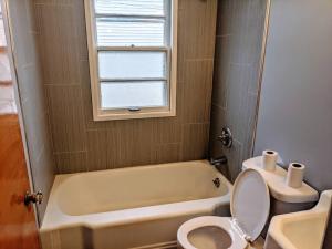 La salle de bains est pourvue d'une baignoire, de toilettes et d'une fenêtre. dans l'établissement Cozy 2 BR House in Davenport, à Davenport