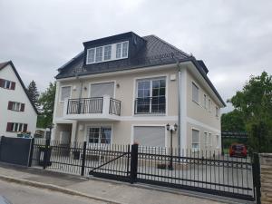 a white house with a black fence at Helle 3 Zimmer Souterrainwohnung in einem Neubau-Villa in Munich