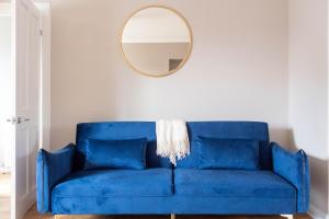 ein blaues Sofa im Wohnzimmer mit Spiegel in der Unterkunft Burns House in Livingston