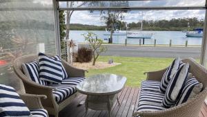 a porch with chairs and a table and a view of the water at Riverview Cottage in Dunbogan